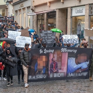 Mesnchen demonstrieren in Tübingen gegen die Äußerungen von OB Palmer zum gewaltsamen Tod eines jungen Gambiers. Dabei tragen sie ein Transparent mit Bilder des Ermordeten.