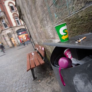 Pappbecher vor und in einem Mülleimer in der Tübinger Innenstadt