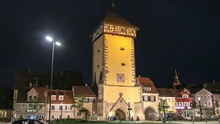 Ein historischer Turm mit Fachwerk am Dachgeschoss in einer Nachtaufnahme