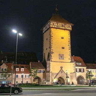 Ein historischer Turm mit Fachwerk am Dachgeschoss in einer Nachtaufnahme