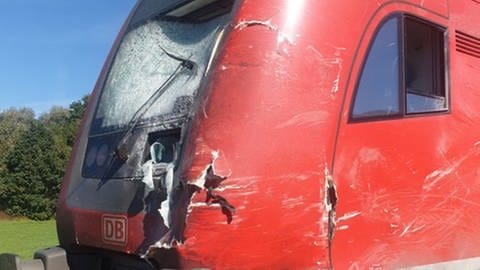 Ein roter Triebwagen der Bahn mit geplitterter Scheibe und starken Beschädigungen