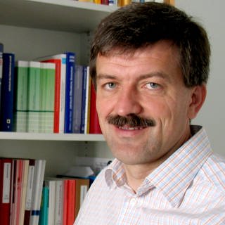Der Strafrechtler Jörg Kinzig sitzt vor einem Regal mit Büchern.