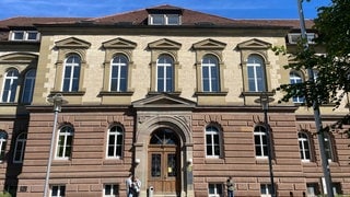 Vereinzelte Menschen stehen vor dem Sandsteinbau in Hechingen