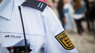 Schulterausschnitt eines Polizeibeamten bei der Streife, sichtbar sind Funkgerät, Schulterklappe und das BW-Wappen am Oberarm.