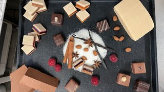 Zutaten für Sigmaringer Huthmacher-Dominosteine: weihnachtliche Gewürze, Schokolade, Marzipan, Früchte und Mandeln.