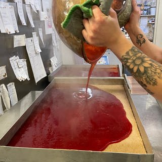 Herstellung der Fruchtfüllung für Dominosteine: Die rote Fruchtsoße - hier Erdbeere - kommt auf ein Blech und wird dann beim Trocknen fest.