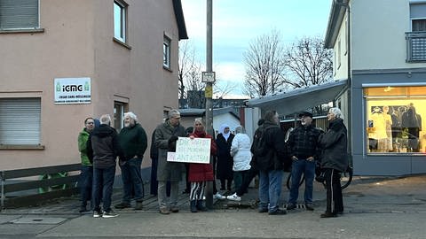 Bei einer Mahnwache vor einer Moschee in Mössingen sind Menschen vor dem Gebäude versammelt und Stadtrat Jochen Gewecke von der SPD hält ein Schild hoch auf dem steht: "Die Würde des Menschen ist unantastbar". 