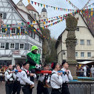 Die Bräutelgesellen tragen einen Neubürger auf einer Stange um den Marktbrunnen in Haigerloch (Zollernalbkreis). 
