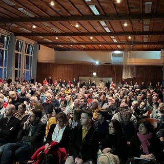 Rund 300 Menschen sitzen im bestuhlten Saal in der Turn- und Festhalle Albstadt-Laufen (Zollernalbkreis)