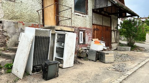 Kaputte Kühlschranke und andere Elektrogeräte stehen vor einem Haus in Bisingen. Die Schäden durch das Hochwasser Anfang Mai sind hoch. 