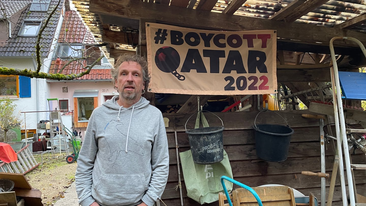 Christoph Leupolz vor einem Banner mit der Aufschrift: Boycott Qatar 2022