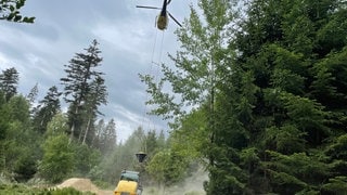 Ein Hubschrauber lässt sich mit Kalk vom Boden beladen