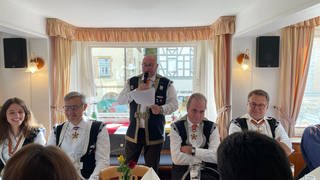 Mitglieder der Narrenzunft Vetter Guser in Sigmaringen sitzen an einem langen Tisch. Der  Zunftmeister Philippe Sutter hält eine reede zur Eröffnung der Fasnet.