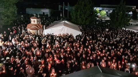 Gottesdienstbesucher der griechisch-orthodoxen Kirche in Reutlingen stehen mit brennenden Osterkerzen vor der Kirche