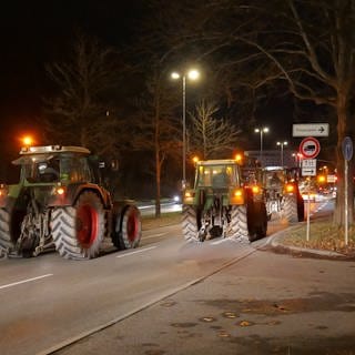 Landwirte mit ihren Traktoren fahren in einem Demonstrationszug durch das nächtliche Tübingen. Sie protestieren gegen die Streichung von Subventionen
