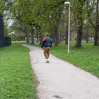 Mann mit Kapuze im Park unterwegs