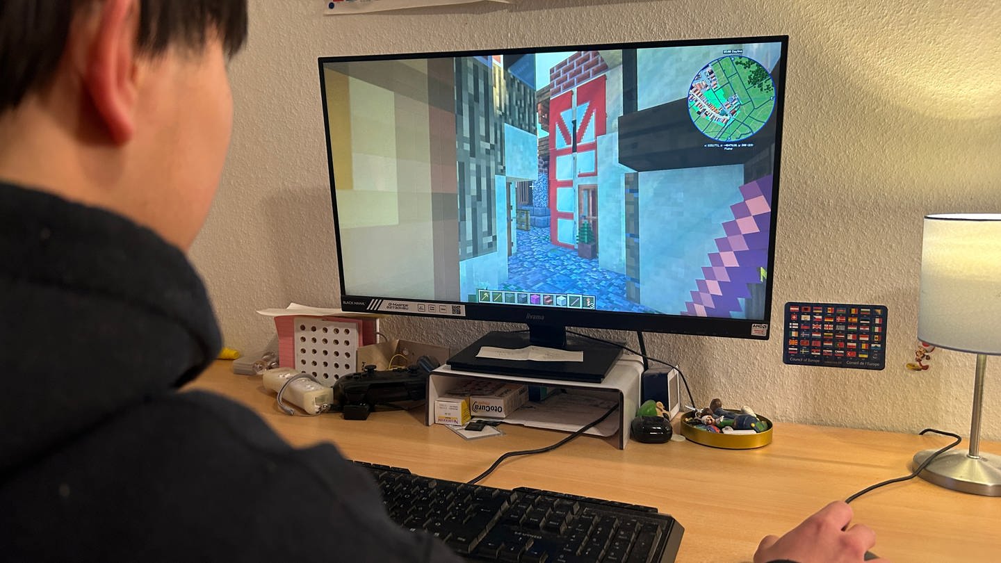 Justin Vu sitzt in seinem Zimmer und klickt sich im Videospiel Minecraft durch das virtuelle Reutlingen.