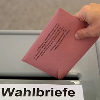Wähler steckt Wahlbrief in eine Wahlurne