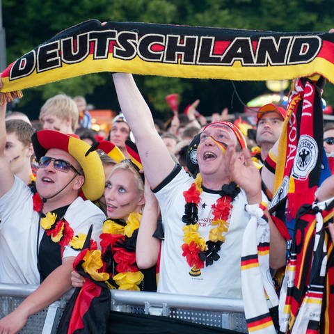 Fußballfans mit Deutschland-Schmuck jubeln. Auch in der Region gibt es zur EM Public Viewing