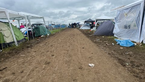 Ein schlammiger Weg auf dem Gelände des Southside Festivals. Links und rechts stehen Zelte.