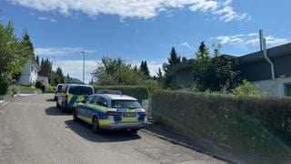 Fahrzeuge der Polizei stehen vor dem Tatort in Albstadt-Lautlingen, an dem am Sonntag drei Menschen durch Schüsse gestorben sind.