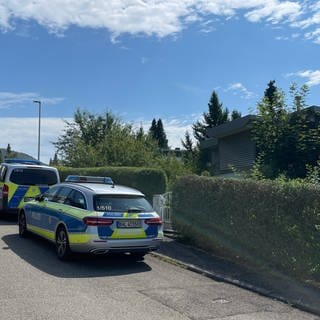 Fahrzeuge der Polizei stehen vor dem Tatort in Albstadt-Lautlingen, an dem am Sonntag drei Menschen durch Schüsse gestorben sind.