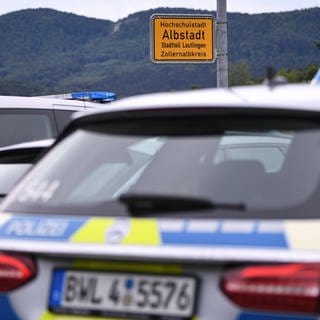 Polizei-Fahrzeuge stehen vor dem Ortsschild in Albstadt-Lautlingen. In dem Ort hat ein Mann sich und seine Schwiegermutter und seinen Sohn mit einer Waffe getötet, seine Frau und seine Tochter überlebten schwer verletzt.