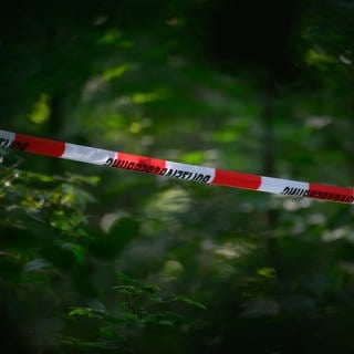Symbolbild: Flatterband der Polizei in einem Wald. Die Todesursache einer Frau, die bei Straßberg gefunden wurde ist noch immer unklar.