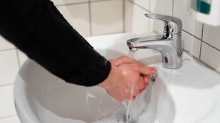 Ein Mann wäscht sich die Hände. Er ist zur stationären Behandlung einer Zwangsstörung, eines Waschzwangs, in einer Klinik.