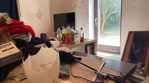 In die Wände der Wohnung wurden Löcher geschlagen. Auf einem Tisch stehen Schnapsflaschen herum.