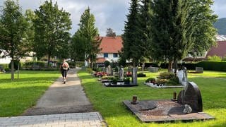 Ein Mann läuft über einen Friedhof. Dort ist am Freitag der Sohn einer Familie aus Albstadt-Lautlingen beigesetzt worden. Er war Opfer eines Tötungsdelikts.