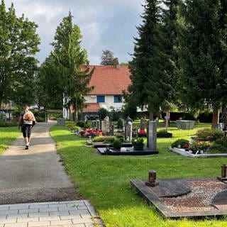 Ein Mann läuft über einen Friedhof. Dort ist am Freitag der Sohn einer Familie aus Albstadt-Lautlingen beigesetzt worden. Er war Opfer eines Tötungsdelikts.