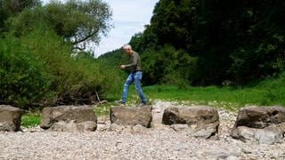 Mann läuft über Steine in einem trockenen Flussbett. Die Donau versickert bei Tuttlingen an 150 bis 200 Tagen. 