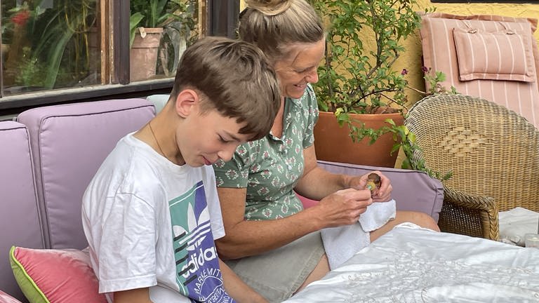 Tierärztin Katrin Wittenberg und Sohn Theo füttern gemeinsam die gefundenen Eichhörnchen-Babys auf der Terrase ihres Hauses.