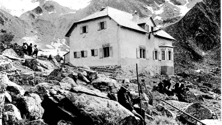 Ein Blick in die Höhe: Eine Schwarz-Weiß-Aufnahme zeigt die Tübinger Hütte am Tag ihrer Einweihung im Jahr 1908.