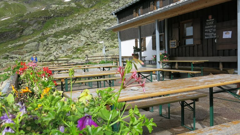 Bierbänke auf gut 2.000 Metern Höhe vor der Tübinger Hütte mit Bergblick laden Wanderer zum Verweilen ein. Zwischen Juli und September wird die Schutzhütte bewirtschaftet.