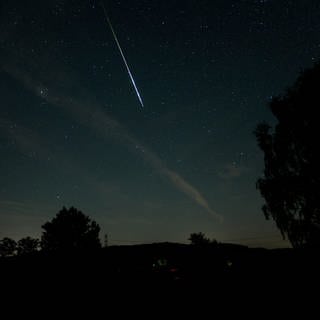 Ein sternklarer Nachthimmel an dem eine große Sternschnuppe zu sehen ist. Ein Perseiden über dem Meteorcamp auf der Schwäbischen Alb bei Münsingen.