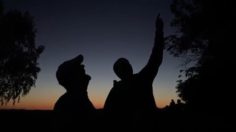 Zwei Männer als Silhouetten vor den letzten Sonnenstrahlen blicken in den Himmel, um die ersten Sterne und Perseiden zu erblicken.