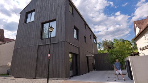 Ein Haus mit dunkler Holzfassade in Ammerbuch. Es ist groß genug für ein Segelflugzeug und zwei Familien.