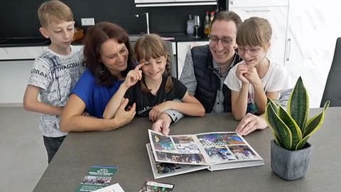 Andreas Braun mit seiner Schwägerin Stefanie Braun und deren Kindern am Küchentisch. Er sitzt im Rollstuhl, weil er vor vielen Jahren einen Feuerwehr-Unfall hatte.