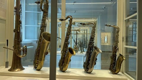 Saxophone in einer Vitrine, dahinter weitere Vitrinen. Erklärt werden die Instrumente am Tag des offenen Denkmals. 