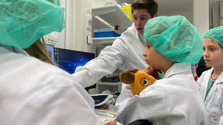 Kinder in Laborkitteln lernen mithilfe der Maus in Laboren der Uniklinik Tübingen das Forschen kennen.