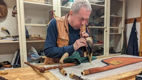 Andreas Rogge bläst in seiner Werkstatt in Rottenburg in eine Pfeife, die zu einem traditionellen deutschen Dudelsack aus dem Mittelalter gehört.