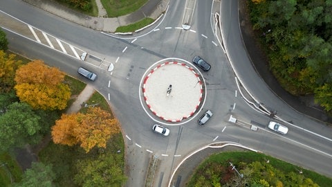 Ein Kreisverkehr in Tübingen von oben. In der Mitte stehen ein Tisch, Stühle, eine Lampe. 