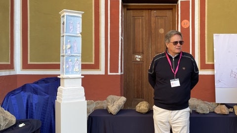 Ein Mann steht neben dem Modell des Denkmals in Hechingen-Stein: Eine weiß-blaue Säule aus der antiken Römerzeit. Das Götterdenkmal haben Archäologen in Hechingen-Stein gefunden.