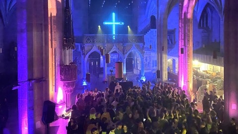 Der Innenraum der Tübinger Stiftskirche erstrahlt durch die Lichtshow auf der Clubnachtparty in leuchtenden Farben – sogar das Kreuz über dem Altar.