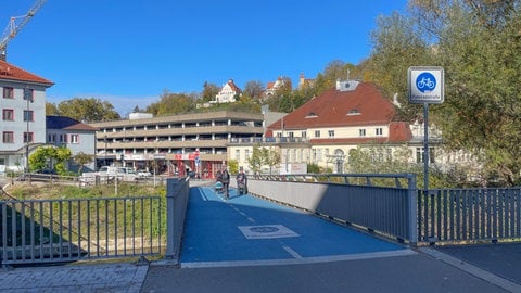 Ein Mann schiebt einen Kinderwagen über die Radbrücke in der Tübinger Innenstadt. Viele Fußgängerinnen und Fußgänger nutzen sie häufig. Eigentlich ist sie als Fahrradstraße ausgewiesen.