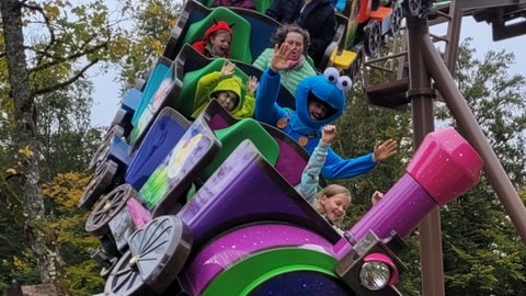 Kinder auf einer Achterbahn im Traumland Sonnenbühl. An Halloween ist der Freizeitpark gruselig geschmückt.