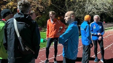 Eine Gruppe von Läuferinnen und Läufern unterhält sich auf der Tartarbahn in Tübingen. Matthias Koch ist Weltmeister im Marathon.