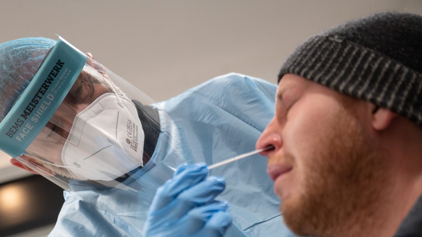 Ein Mitarbeiter führt in einer Teststelle einen Corona-Schnelltest an der Nase eines Mannes durch.